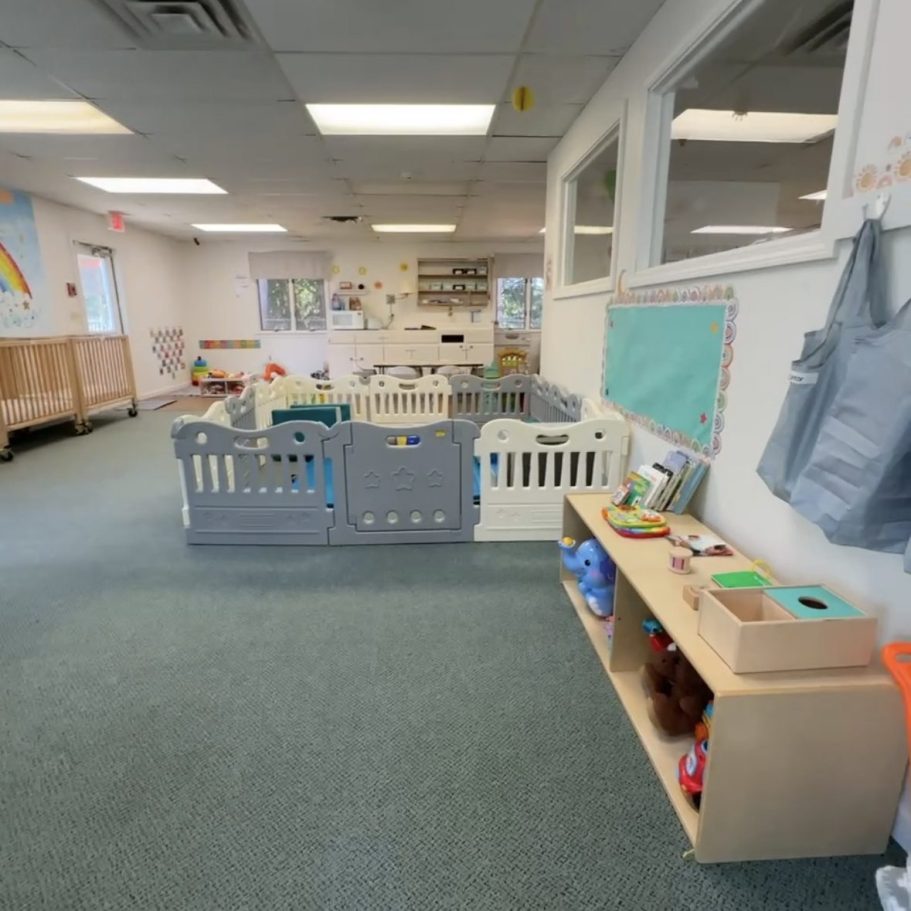 Photo displaying play pen, cribs, toys and view of the infant room.