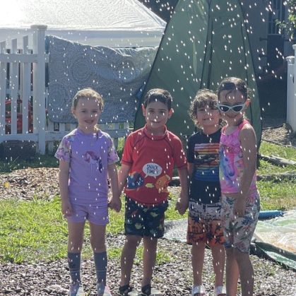 Children smiling in a sprinkler