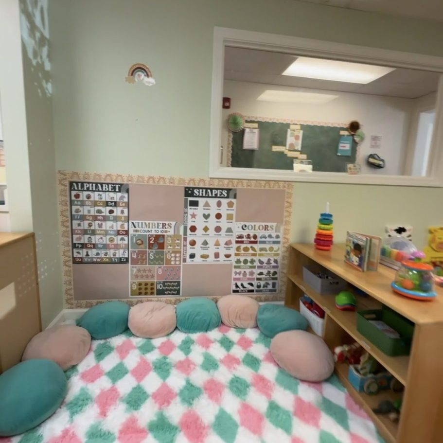 Comfy rug with pillow seats and alphabet, numbers, shapes and colors decorations on the wall.