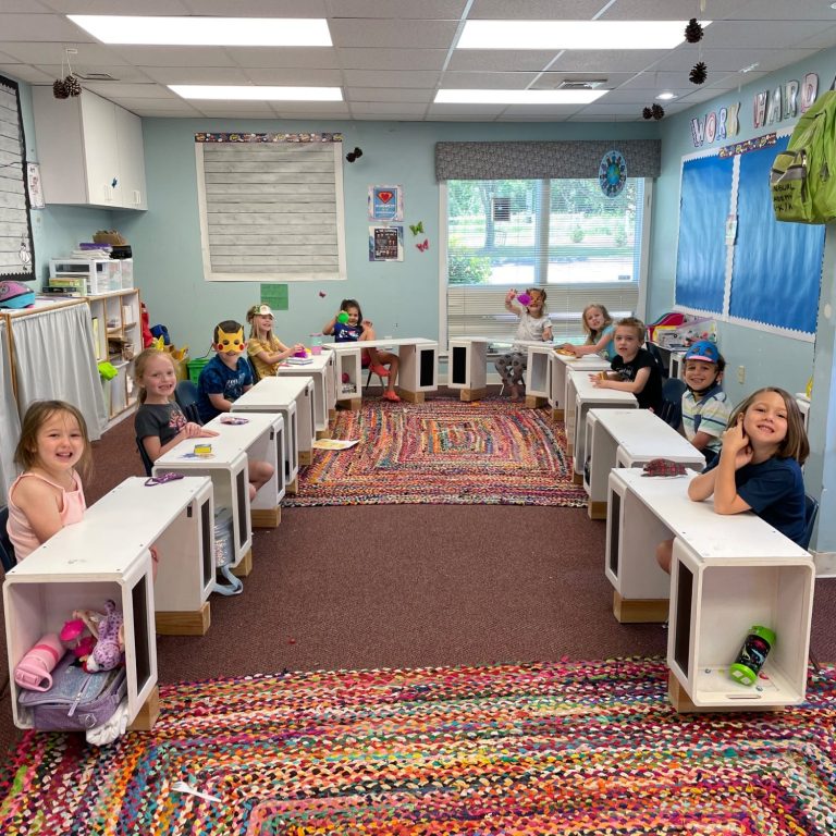 Children seated at individual desks smiling