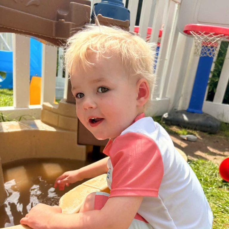 Toddler playing with water table outdoors.