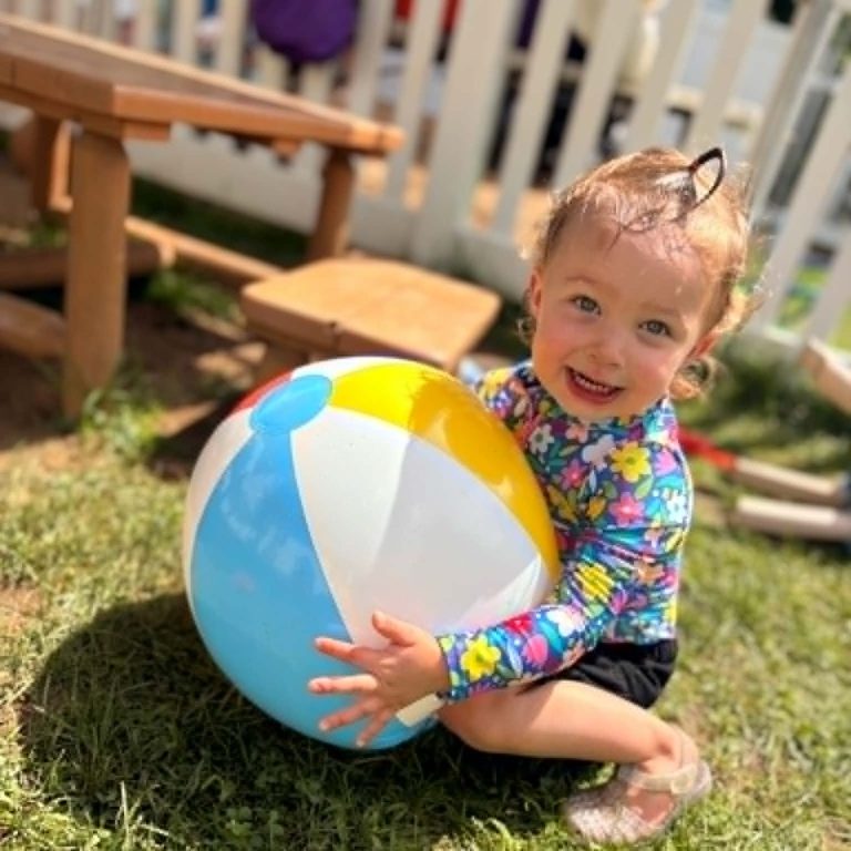 Toddler playing outside with beach ball.