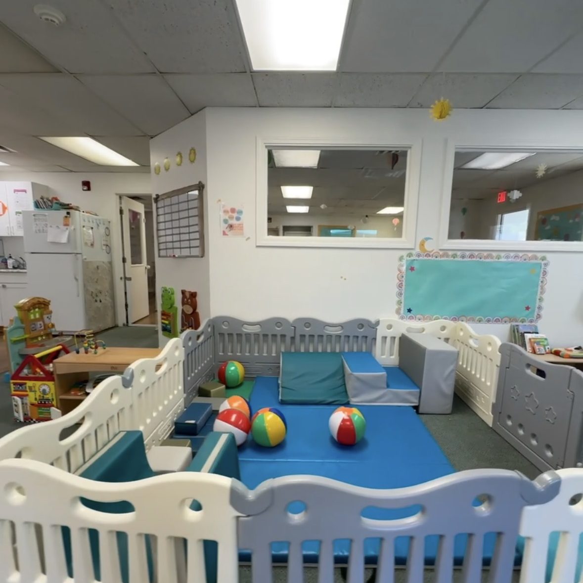 Photo displaying play pen with beach balls, padded blocks and toys.