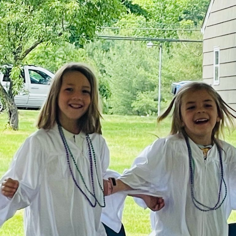 Two children in caps and gowns excited about graduation